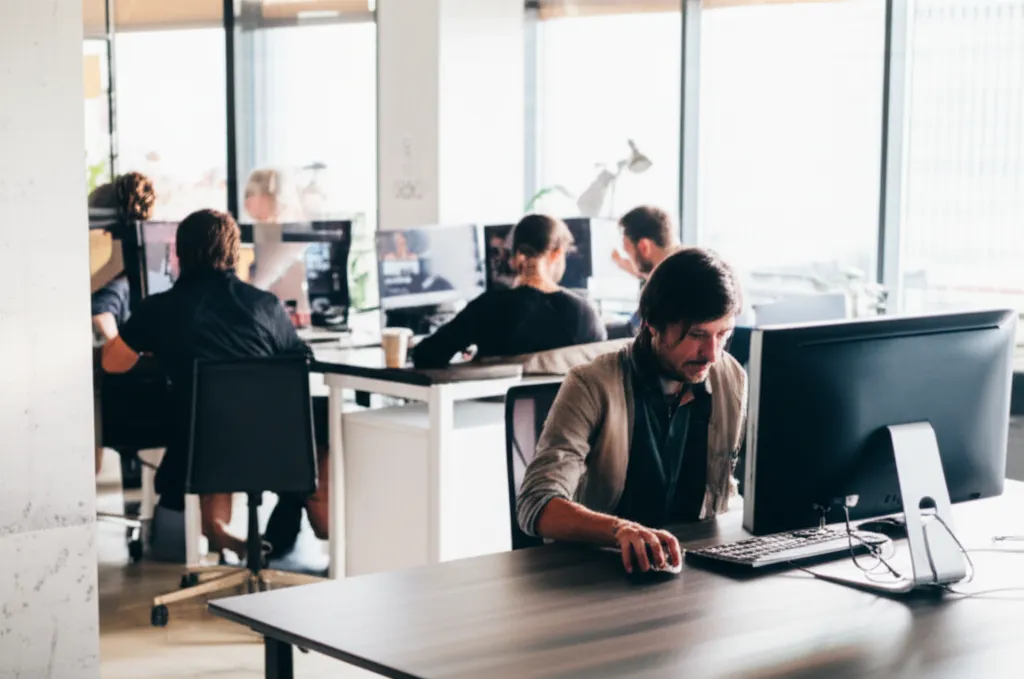 Professional photos of people working in modern office environments, showing individuals focused on their screens and engaged