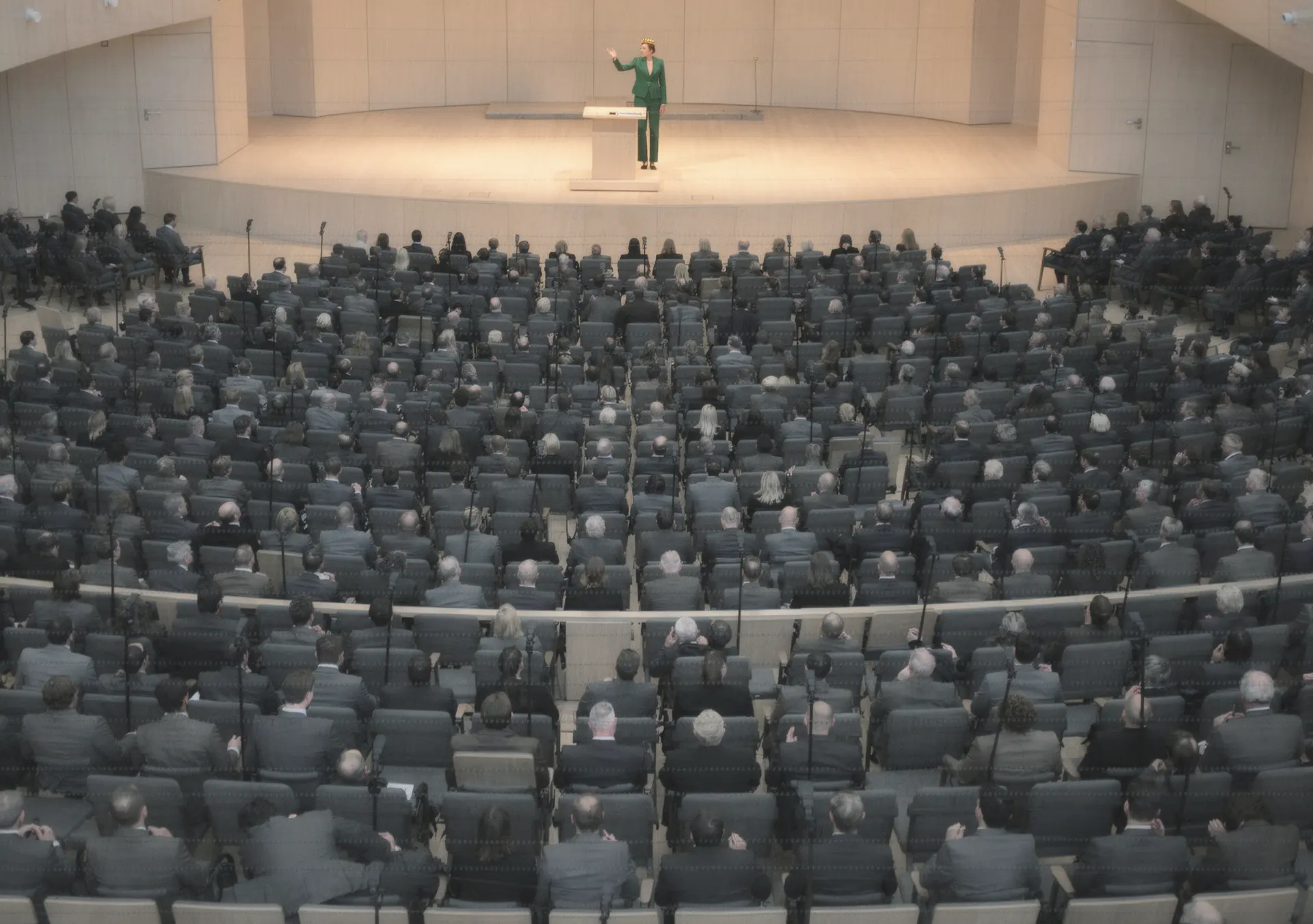 The Queen on stage in a full auditorium, addressing hundreds of seated Workers